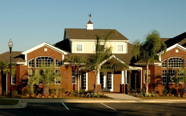 The clubhouse at Cypress Cove Apartments in golden light with palms and flower beds